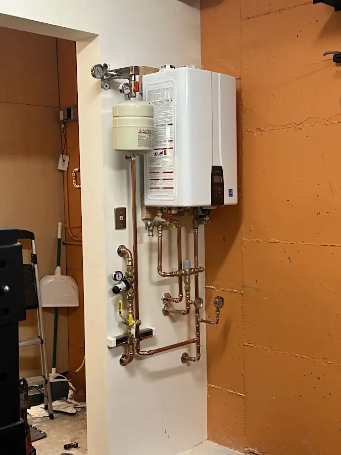 Plumbing technician inspecting water heater connections in Long Lake